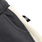 Vista detallada de los pantalones cortos de chándal BVB Colorblock II para niños, en diseño negro y beige, con el logotipo del BVB visible en el bolsillo.