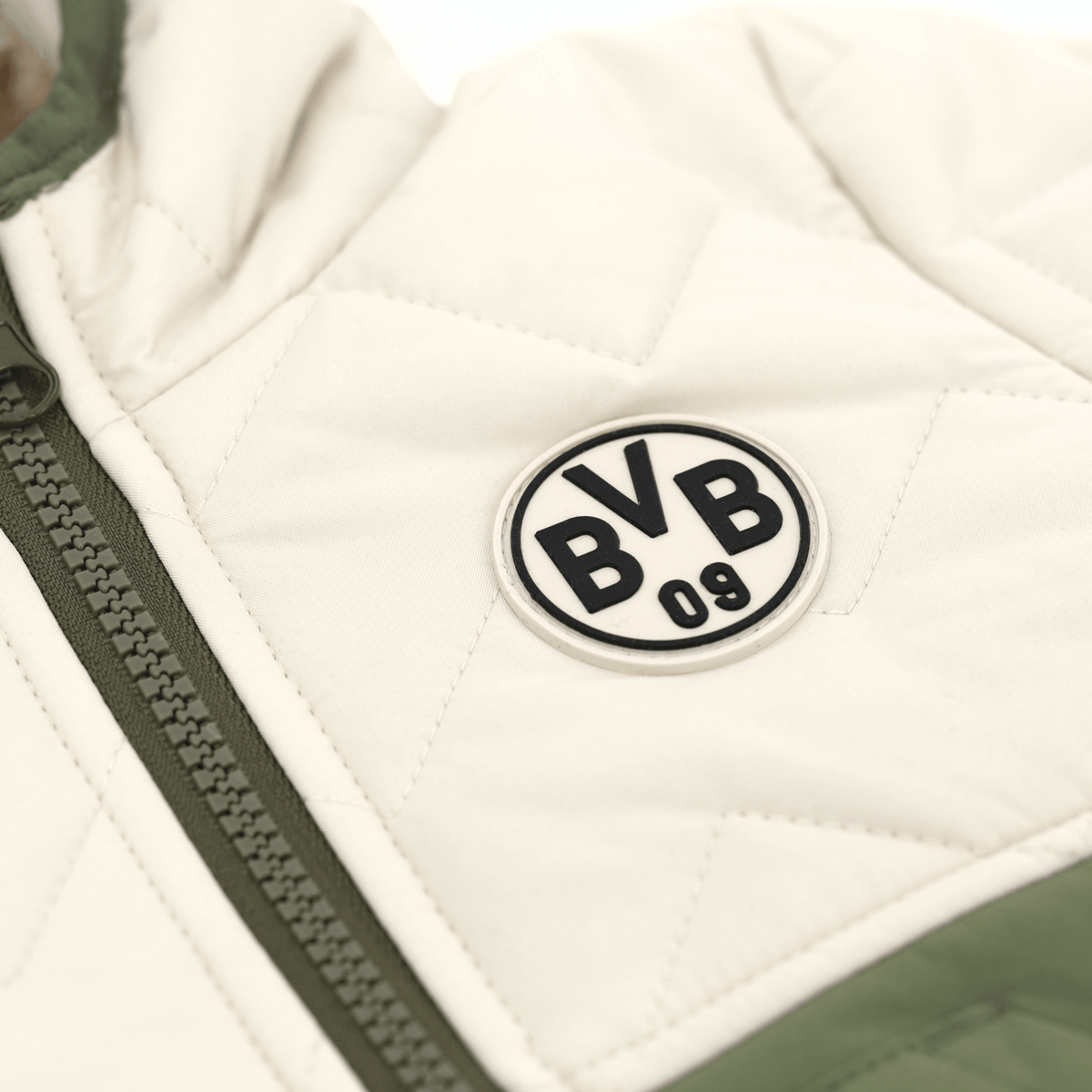 Gros plan sur la veste d'hiver BVB pour bébés et jeunes enfants, bicolore (blanc et kaki), avec le logo BVB 09 cousu et une fermeture à glissière.