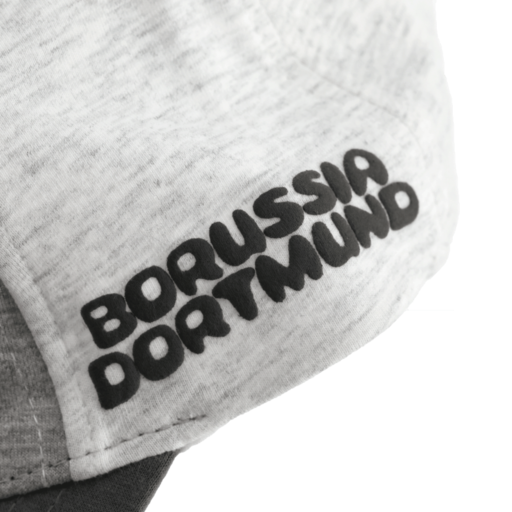 Gros plan sur une casquette pour bébés et jeunes enfants arborant l'inscription « Borussia Dortmund » en noir et jaune et présentant un design « color block ».