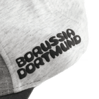 Gros plan sur une casquette pour bébés et jeunes enfants arborant l'inscription « Borussia Dortmund » en noir et jaune et présentant un design « color block ».