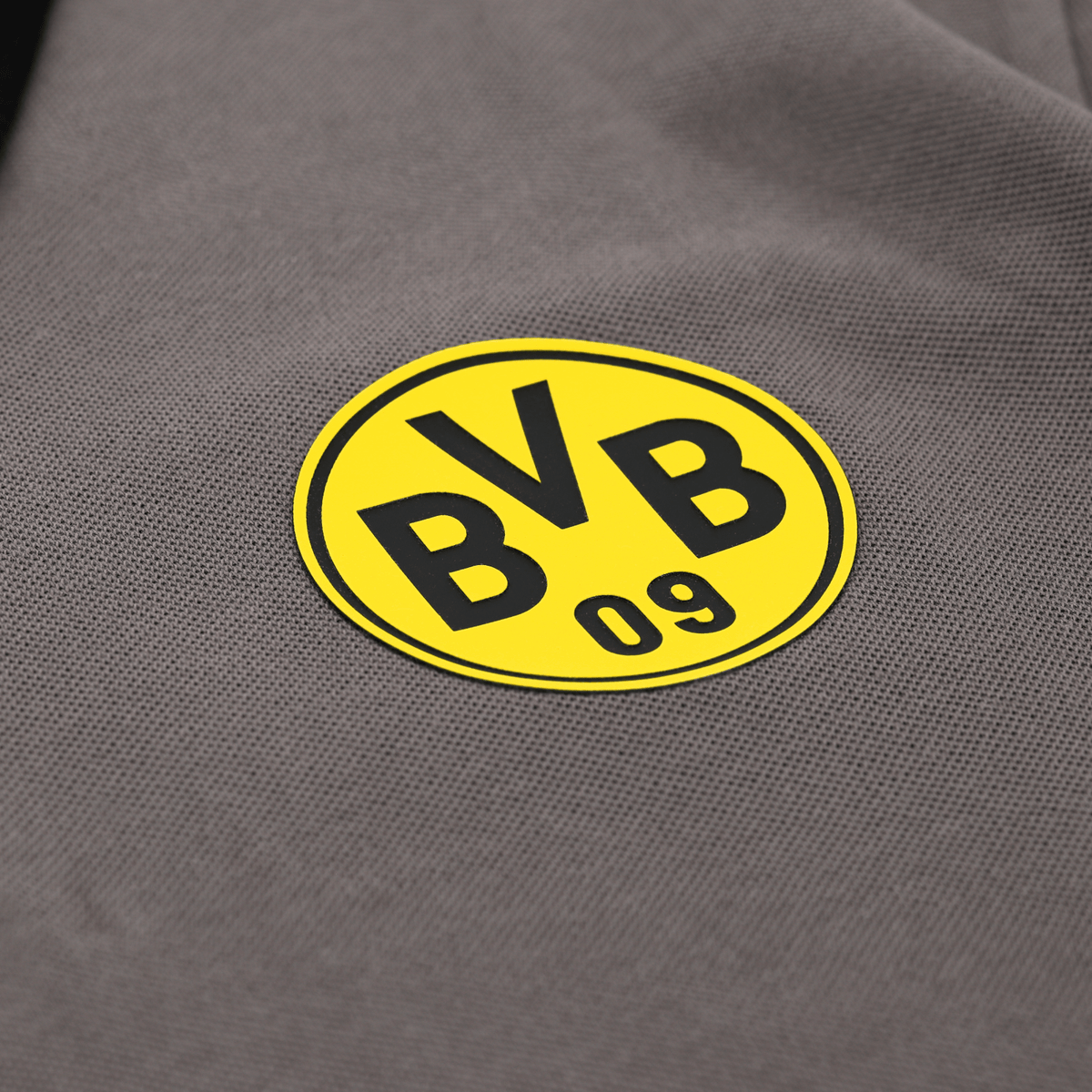 Close-up of a gray polo shirt featuring the yellow BVB logo, sold as fan merchandise.