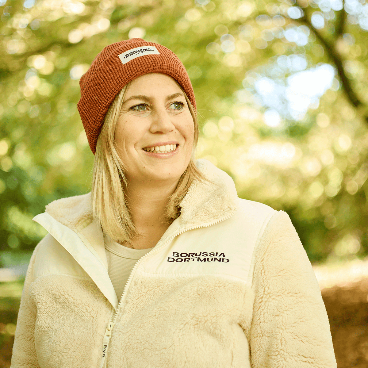 Eine Frau trägt eine orangefarbene BVB Mütze von New Era im Waffle-Design. Ideal für Herbst und Outdoor-Aktivitäten.