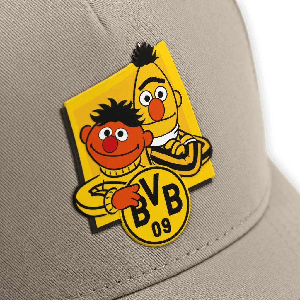 『セサミストリート』のバートとアーニーのプリントが入り、BVB 09のロゴがあしらわれた、メンズ用ベージュのベースボールキャップ。