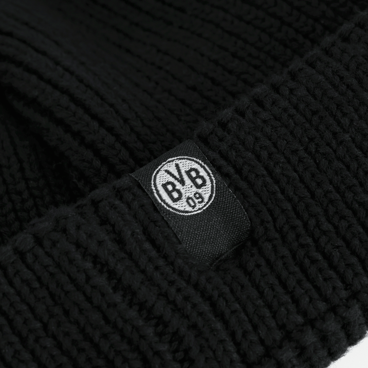 Schwarze BVB Fischerbeanie mit auffälligem BVB-Logo auf einem gewebten Etikett; ein stilvolles Fan-Accessoire für Borussia Dortmund Fans.