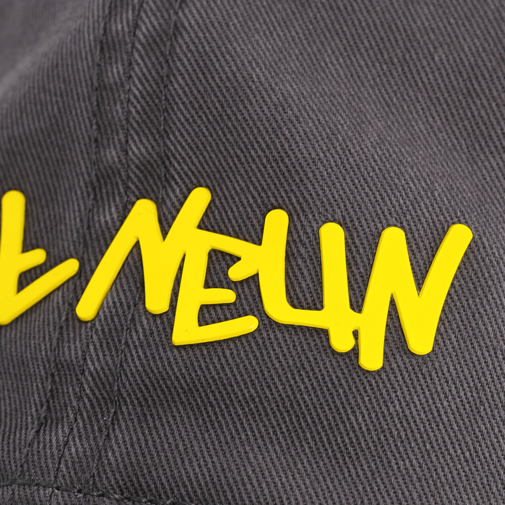 Vista dettagliata di un cappellino del BVB per bambini piccoli, di colore nero con un accattivante motivo graffiti giallo.