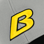 Vista dettagliata di un cappellino grigio del BVB con un vistoso logo “B” nero e giallo, articolo per i tifosi del Borussia Dortmund.