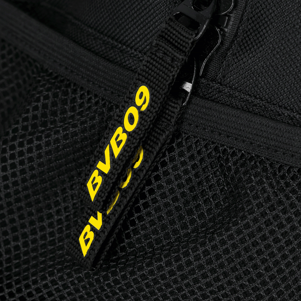 Gros plan sur un sac à dos noir du BVB au design en maille, avec l'inscription « BVB09 » en jaune sur la fermeture à glissière.