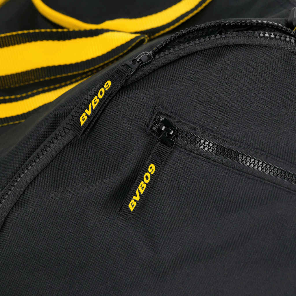Sac de sport BVB noir avec des touches noir et jaune et le logo BVB09 sur les fermetures éclair, idéal pour les supporters et le sport.