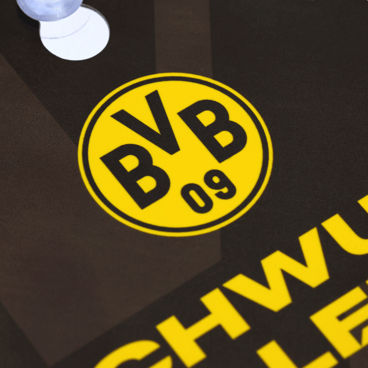 La photo montre un panneau noir et jaune du BVB arborant le logo emblématique du Borussia Dortmund et portant l'inscription « Les jeunes talents sont de la partie ».