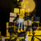 Un folletto da poltrona del BVB nei colori nero e giallo della squadra, posizionato in modo decorativo tra scatole regalo e decorazioni natalizie.