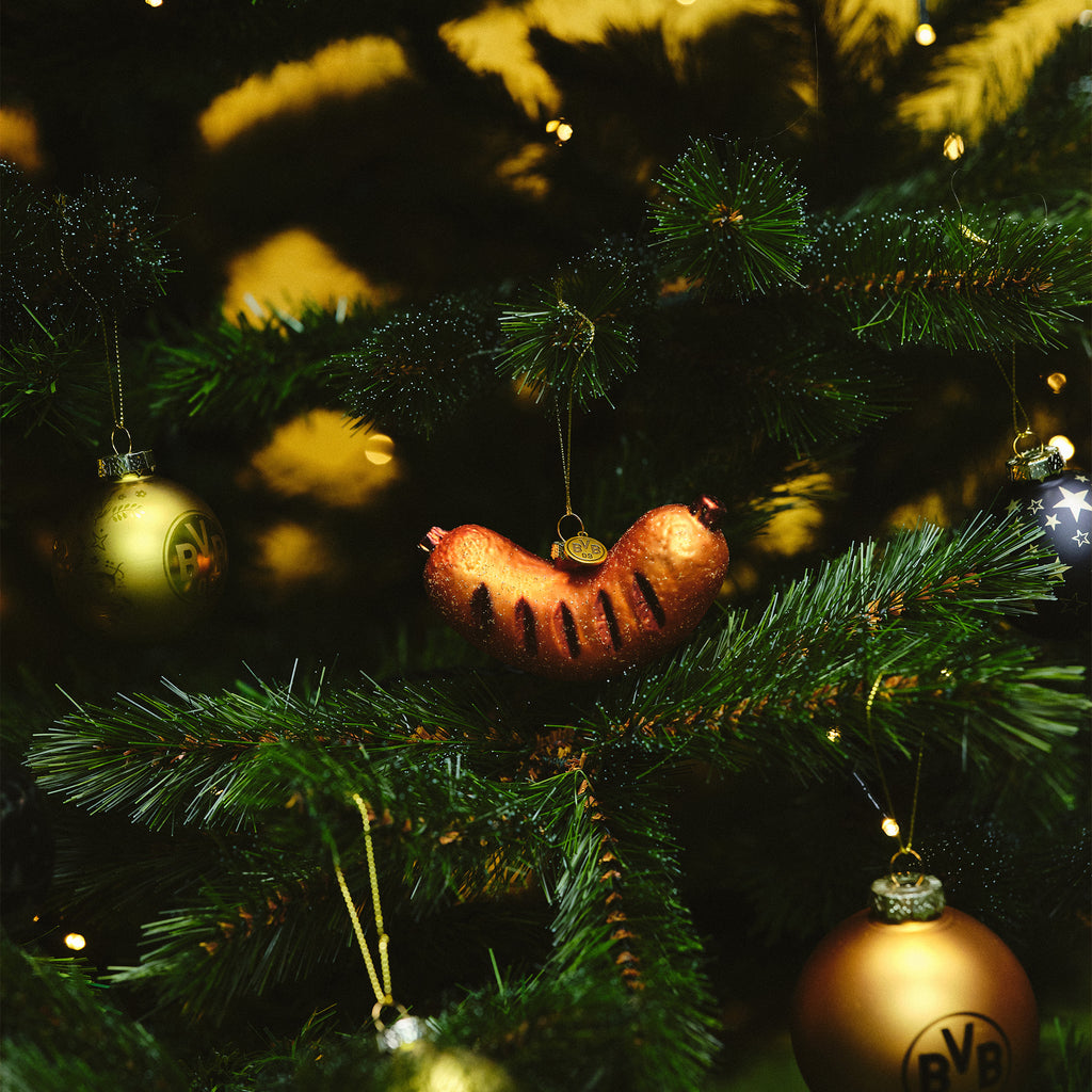 Weihnachtsbaum mit BVB-Dekoration, darunter eine Kugel in Form einer Bratwurst und weitere Kugeln in schwarzgelb und gold.
