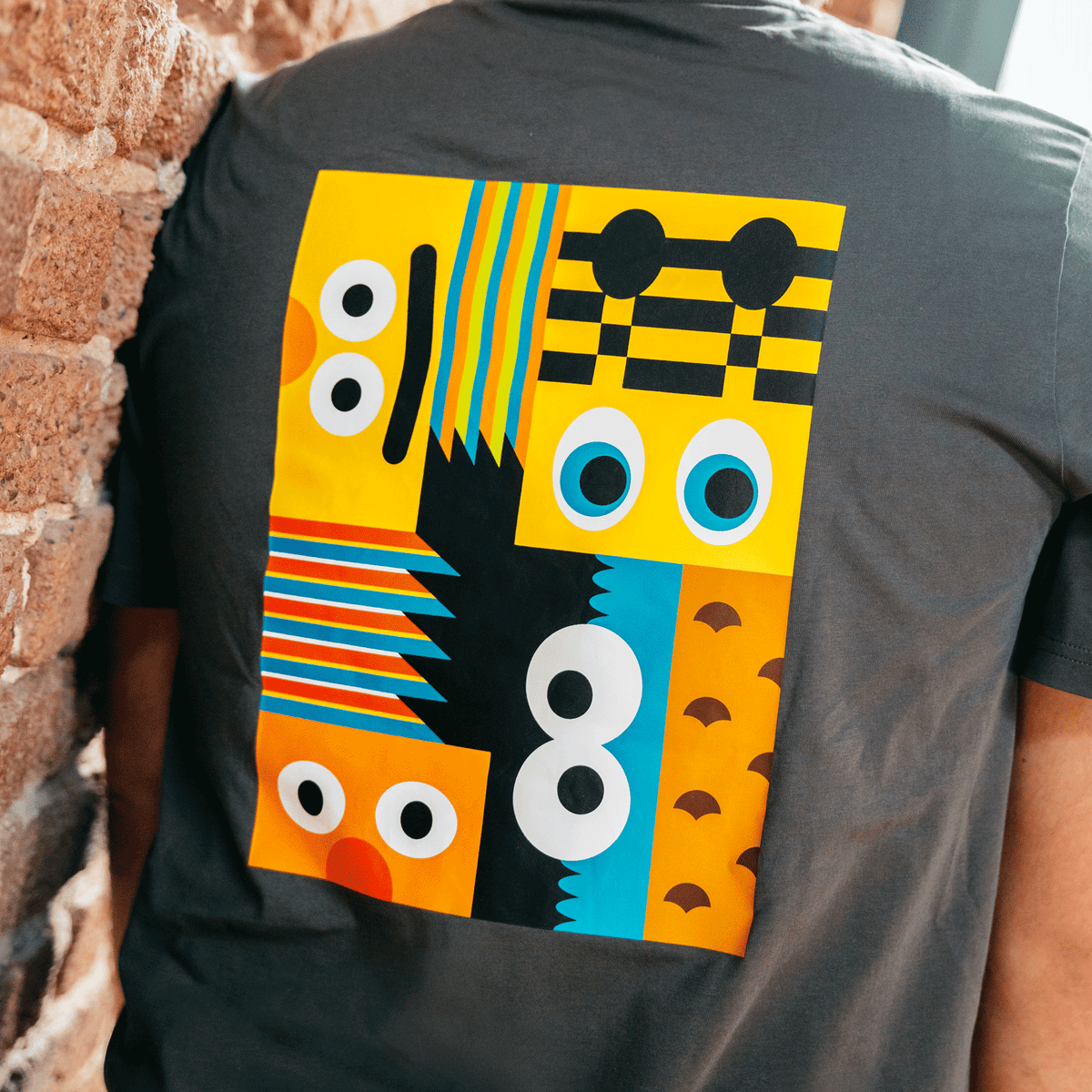 BVB×セサミストリートコレクションのグレーのメンズTシャツ。背面にカラフルで抽象的なデザインが施されています。