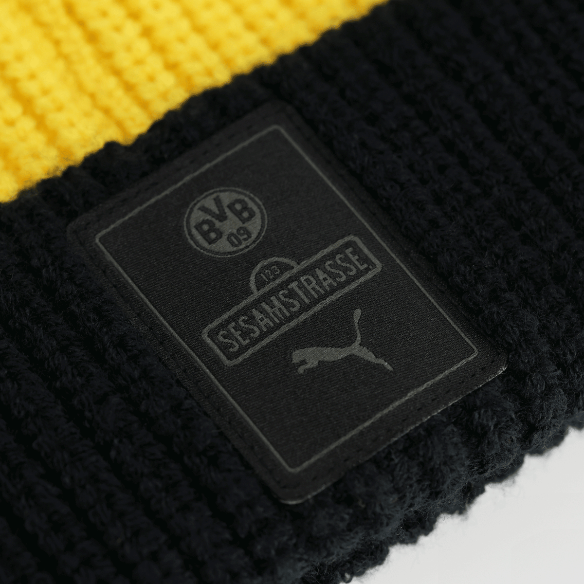 Nahaufnahme der schwarzgelben BVB Sesamstraße Beanie für Kinder mit BVB-Emblem, Sesamstraße-Schriftzug und PUMA-Logo auf dem Etikett.