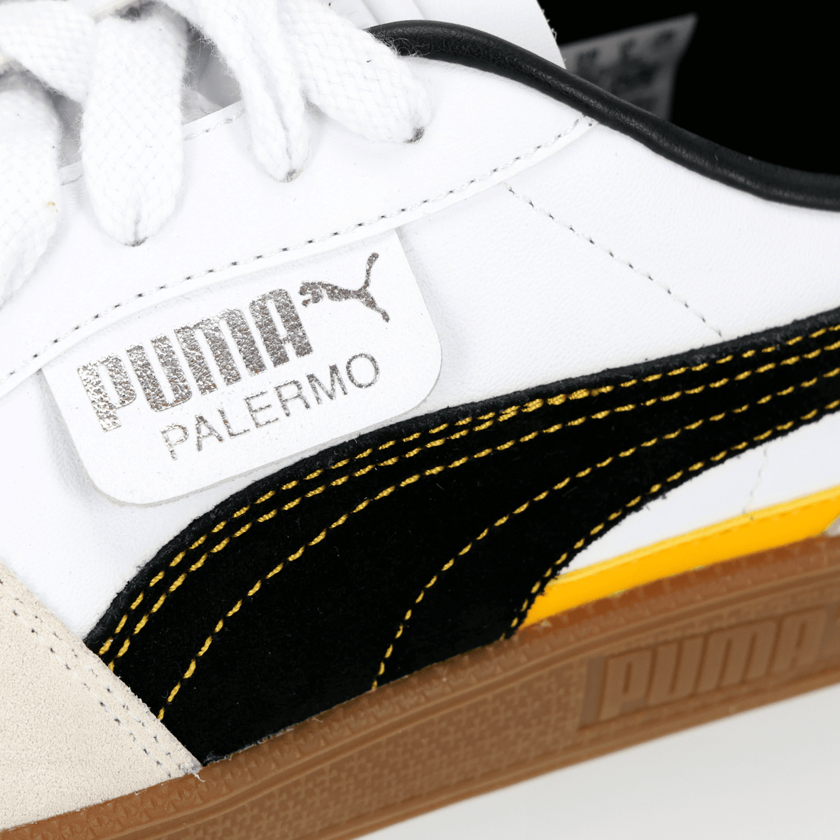 Close-up of a pair of BVB Puma Palermo sneakers with a white upper, black-and-yellow accents, and the Puma logo—perfect for Borussia Dortmund fans.
