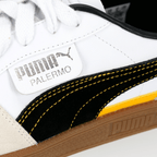Close-up of a pair of BVB Puma Palermo sneakers with a white upper, black-and-yellow accents, and the Puma logo—perfect for Borussia Dortmund fans.