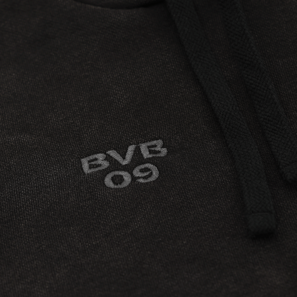 Schwarzer BVB PUMA Ess Elevated Hoodie für Frauen, Nahaufnahme des gestickten BVB 09-Logos auf der Vorderseite.