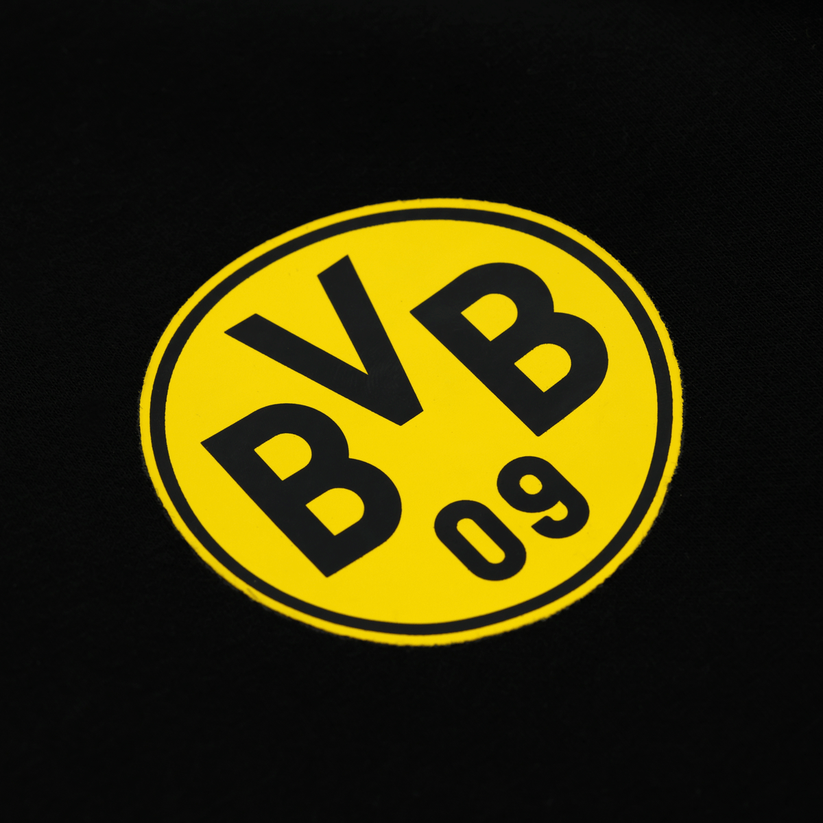Gros plan sur un sweat-shirt de travail du BVB, de couleur noire, arborant un logo BVB jaune bien visible sur le devant.