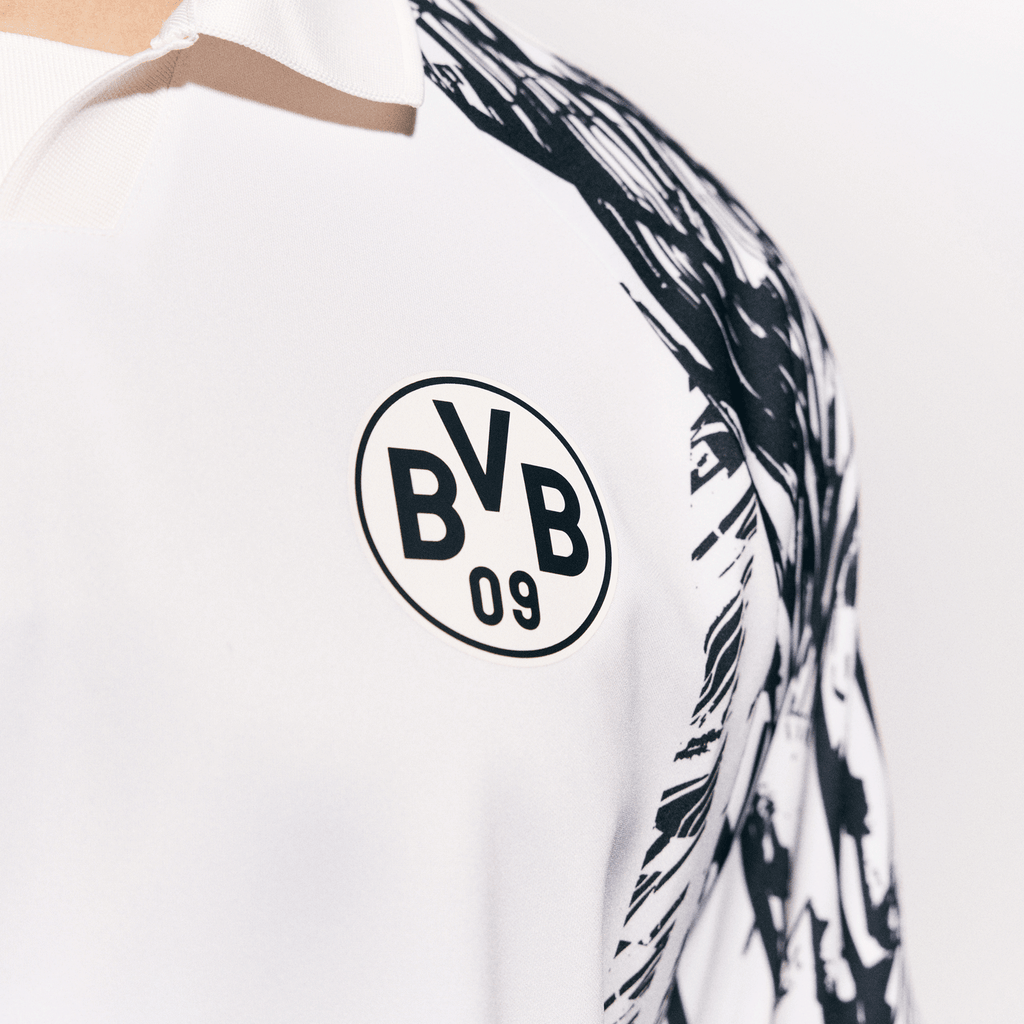 Primo piano della maglia bianca del BVB King con il logo nero "BVB 09" sul petto e un motivo astratto in bianco e nero sulla spalla.