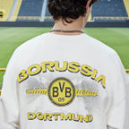 Sweat-shirt blanc BVB x Guess, vu de dos, avec un grand logo BVB jaune, l'inscription « Borussia Dortmund » et un motif noir et jaune.