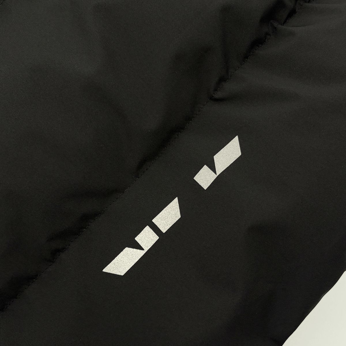 Immagine ravvicinata di una giacca invernale per bambini del Borussia Dortmund nei colori nero e giallo, con il logo BVB ben visibile.