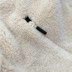 Gros plan sur une veste en polaire Teddy de couleur crème, dotée d'un cordon de serrage et d'une texture douce et moelleuse.