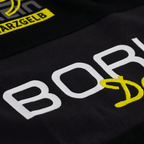 黄色と白のBVBロゴが刺繍され、クラブのモチーフをあしらった、黒のBVB Elements II ポロシャツの詳細画像。