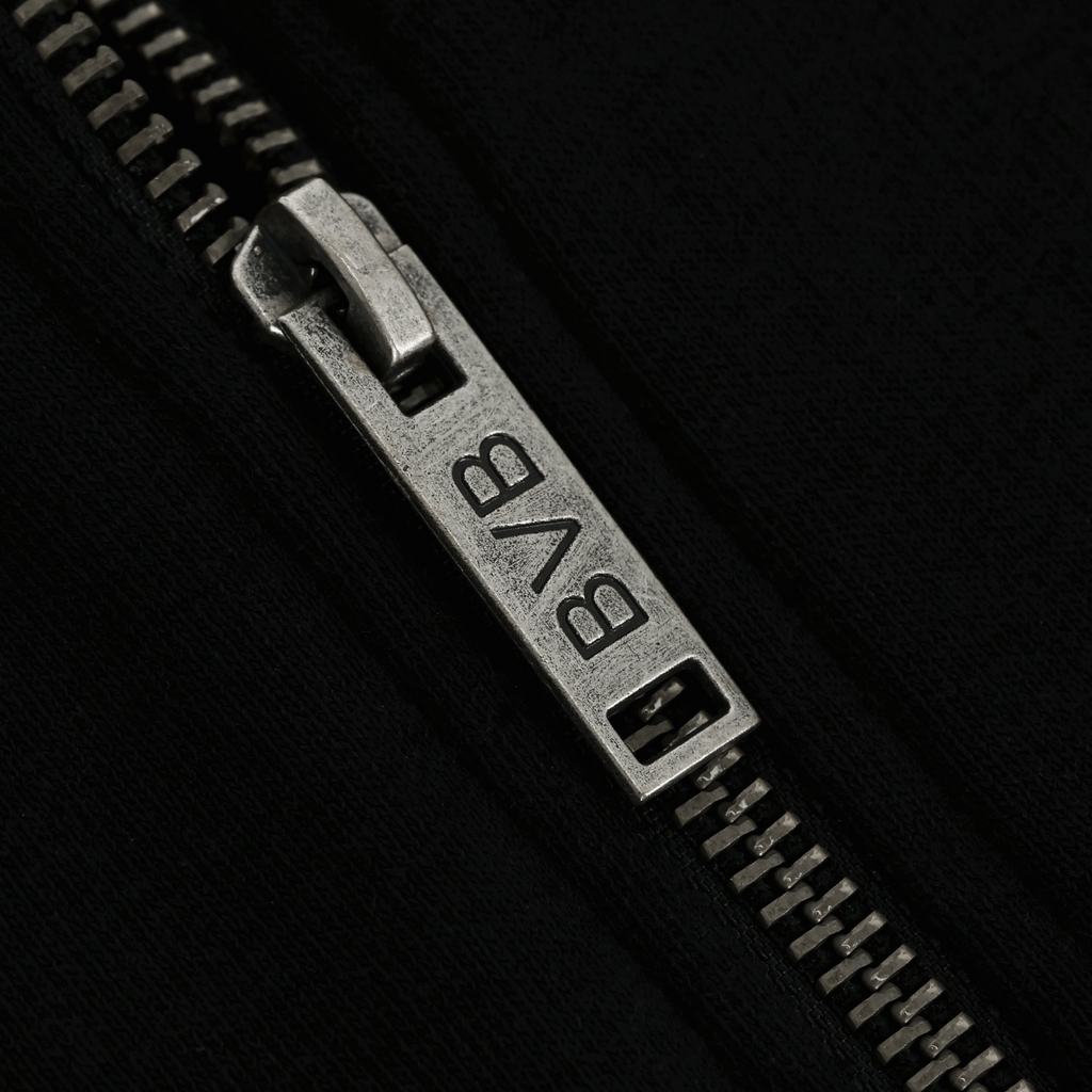 Gros plan sur un curseur de fermeture éclair argenté arborant le logo du BVB, sur une veste de survêtement noire BVB Elements II.