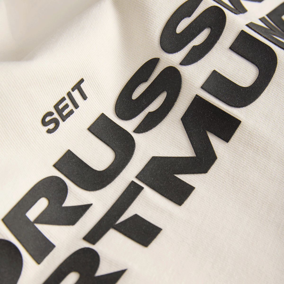 ベージュ色のBVB Tシャツ「Essentials II」に、黒い文字で「Seit Borussia Dortmund」と書かれた部分をクローズアップした写真。ボルシア・ドルトムントのファンアイテム。