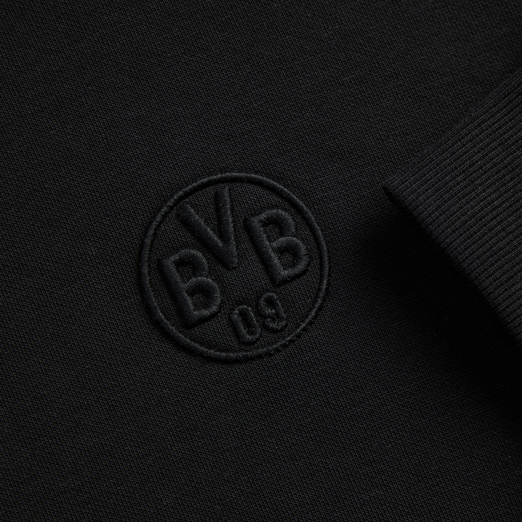 Schwarzer BVB-Hoodie Essentials II mit gesticktem BVB-Logo, Detailaufnahme vom Logo und Ärmel.