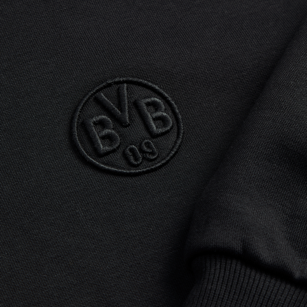La giacca in felpa nera Essentials II del BVB mostra, in primo piano, il logo BVB 09 ricamato: un elegante capo imperdibile per i tifosi del Borussia Dortmund.