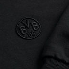 La giacca in felpa nera Essentials II del BVB mostra, in primo piano, il logo BVB 09 ricamato: un elegante capo imperdibile per i tifosi del Borussia Dortmund.