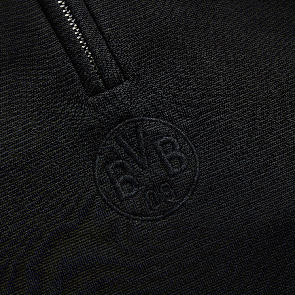 Vista detallada del jersey negro Essentials II del BVB, con el logotipo «BVB 09» discretamente bordado en la parte delantera.