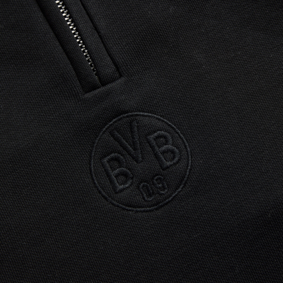 Vista detallada del jersey negro Essentials II del BVB, con el logotipo «BVB 09» discretamente bordado en la parte delantera.