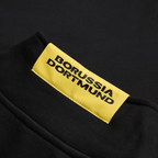 Primer plano del jersey negro Essentials II del BVB con el logotipo amarillo del Borussia Dortmund en la parte delantera.