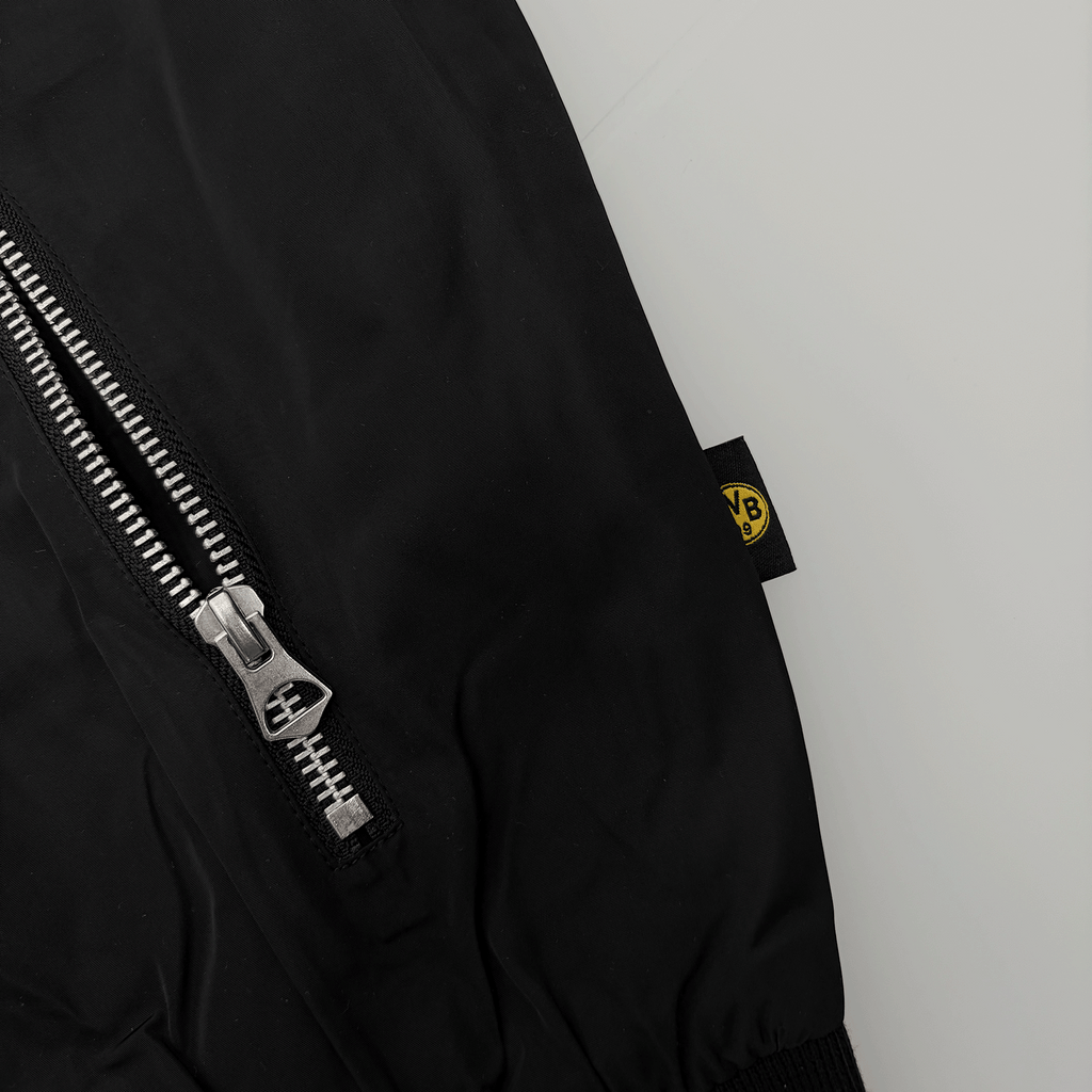 ジッパーが表に出ている、黒と黄色のBVBラベルが付いた「Essentials II」のBVBジャケットのクローズアップ。