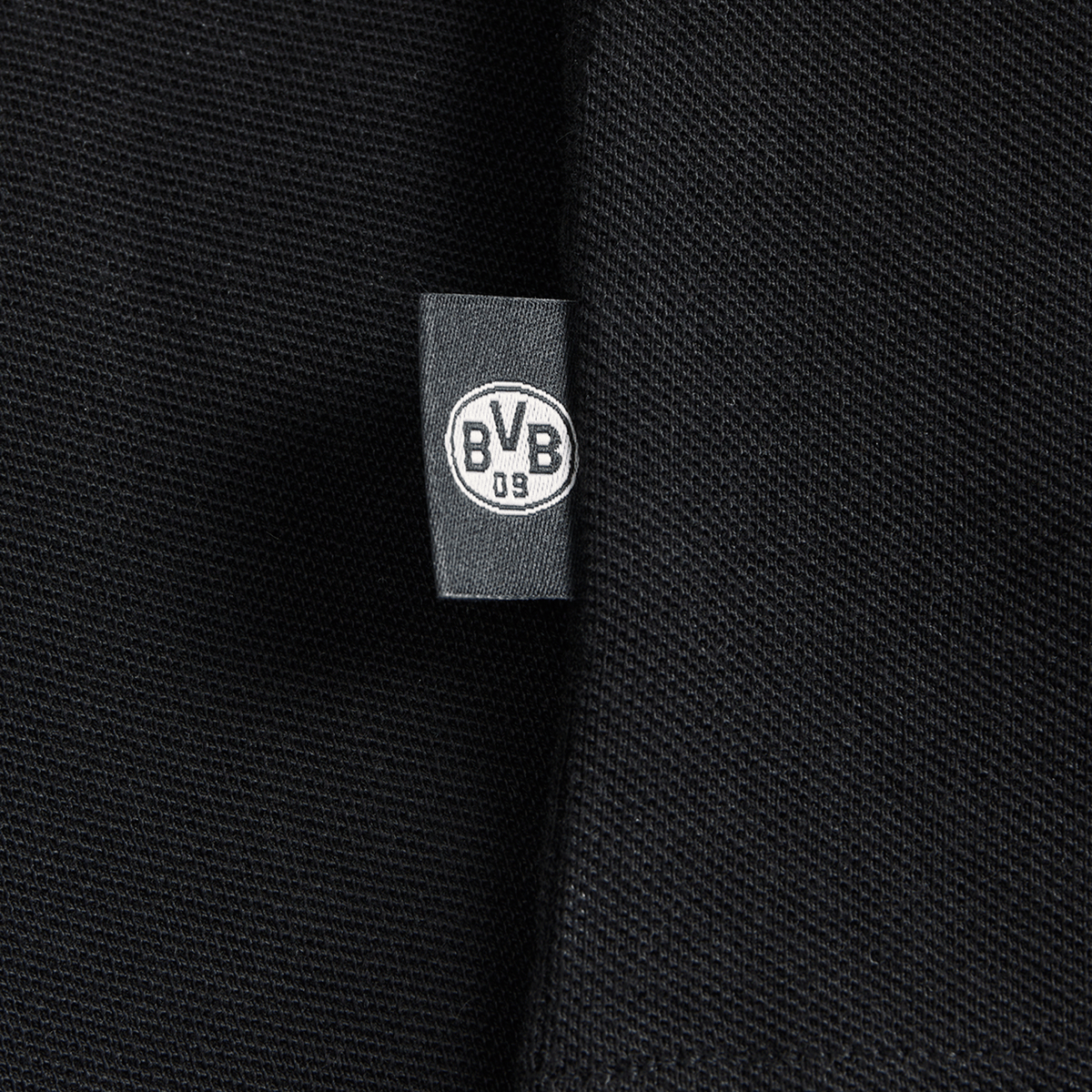 Primo piano di un tessuto nero con il logo del BVB su un'etichetta, ideale per i tifosi del Borussia Dortmund.