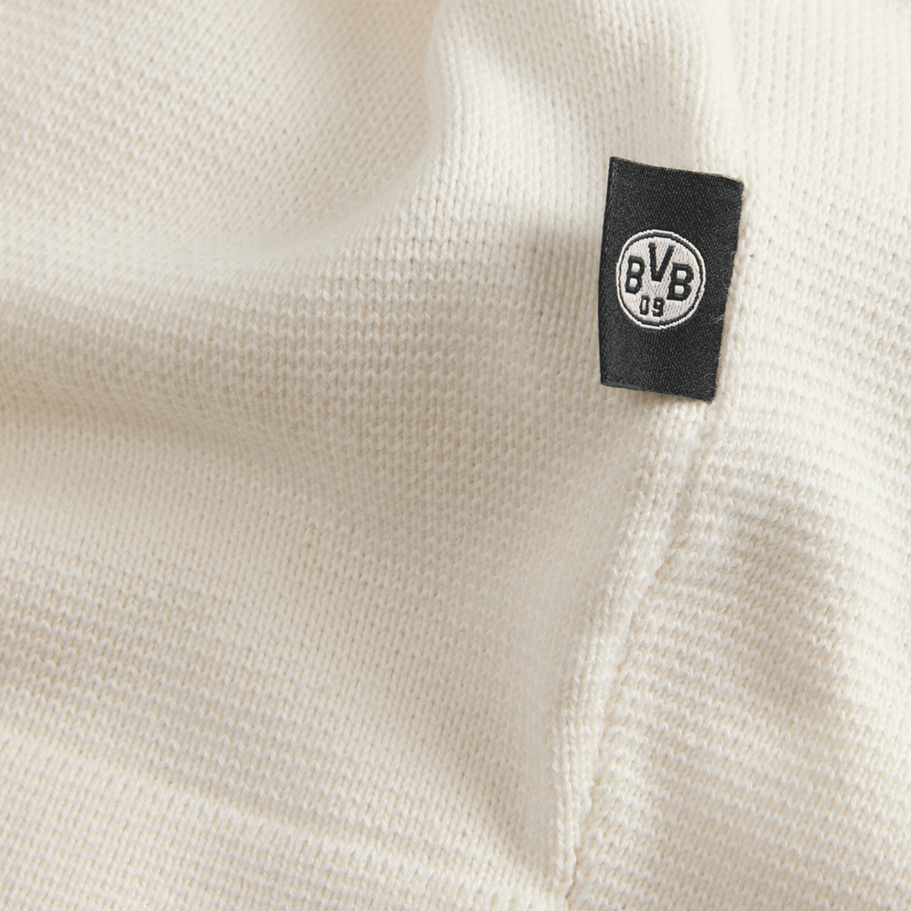 Primo piano di un tessuto a maglia bianco con etichetta nera del BVB, perfetto per i tifosi del Borussia Dortmund.