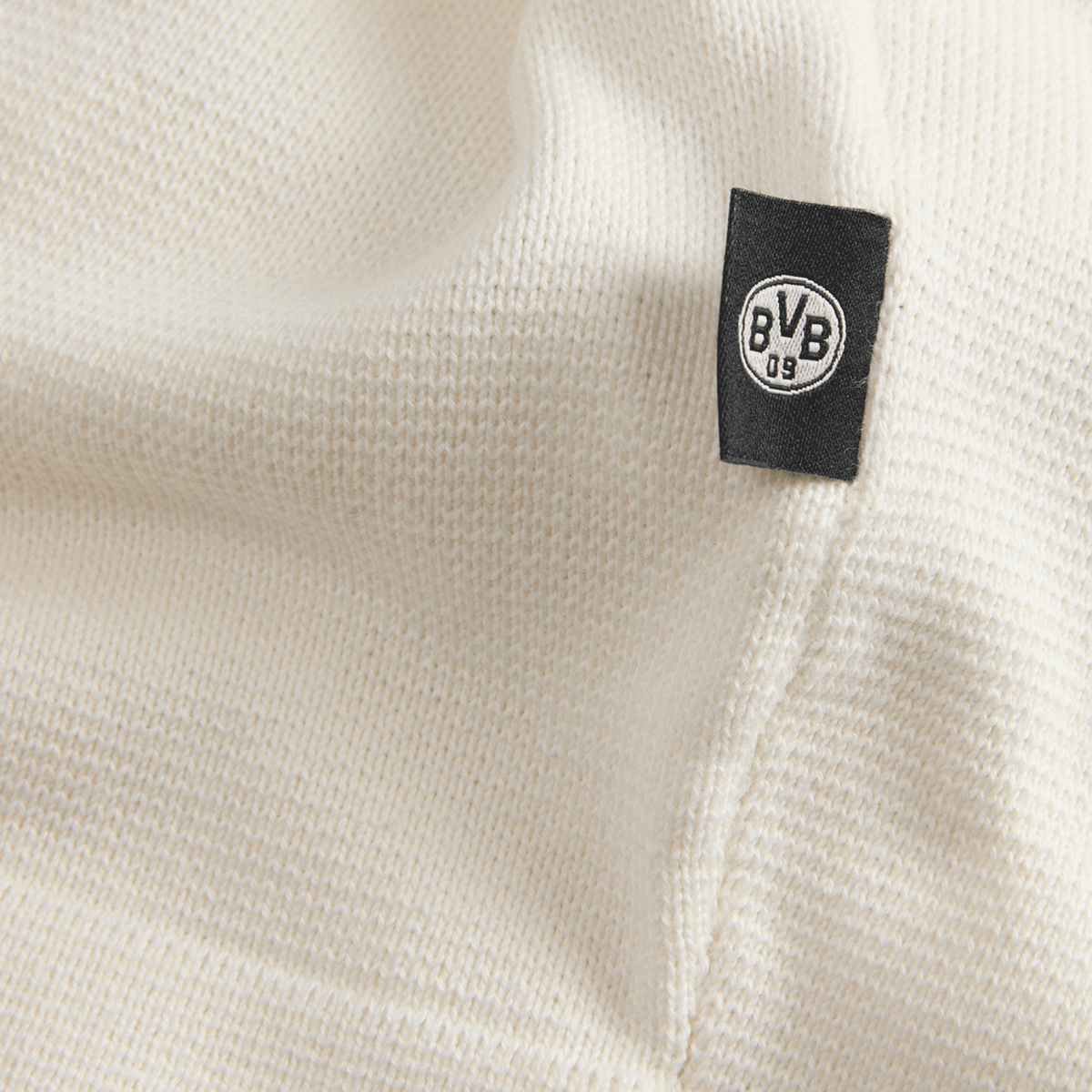 Primo piano di un tessuto a maglia bianco con etichetta nera del BVB, perfetto per i tifosi del Borussia Dortmund.