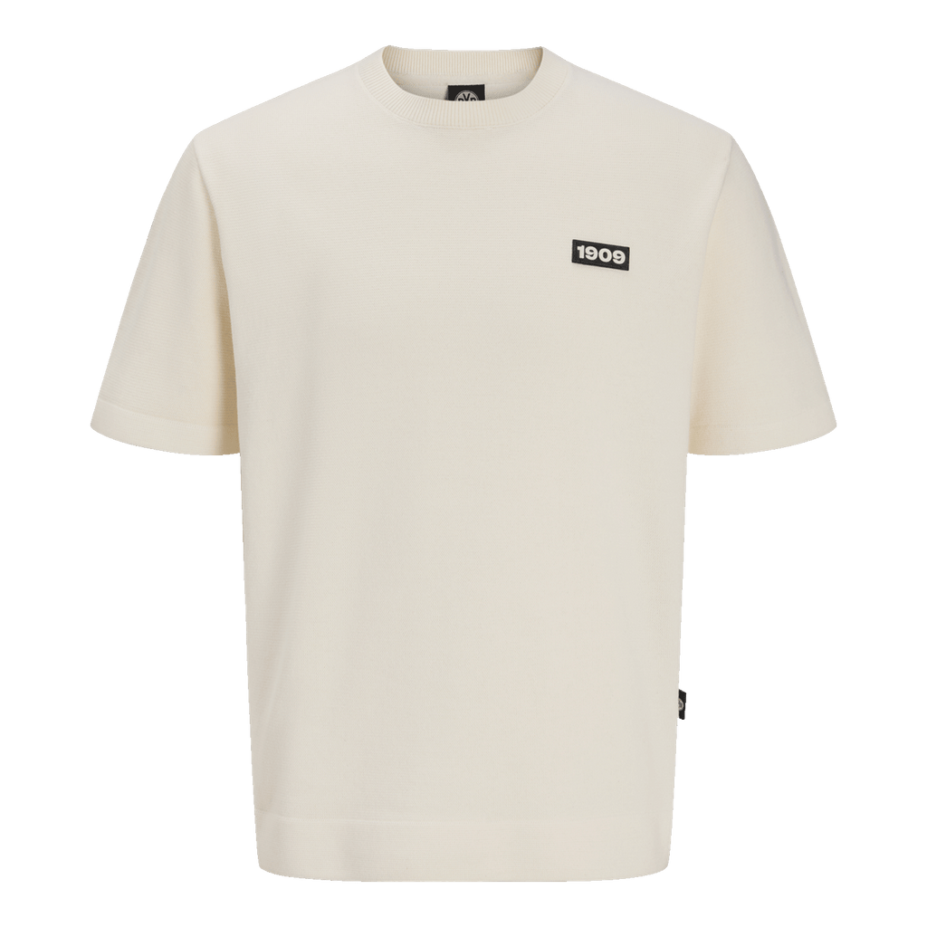 Maglietta color crema con toppa rettangolare nera e la scritta bianca “1909” sul petto, design semplice, maniche corte.