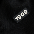 Detailaufnahme eines BVB-Textilstücks in Schwarz mit erhabenem 1909-Emblem in Weiß.