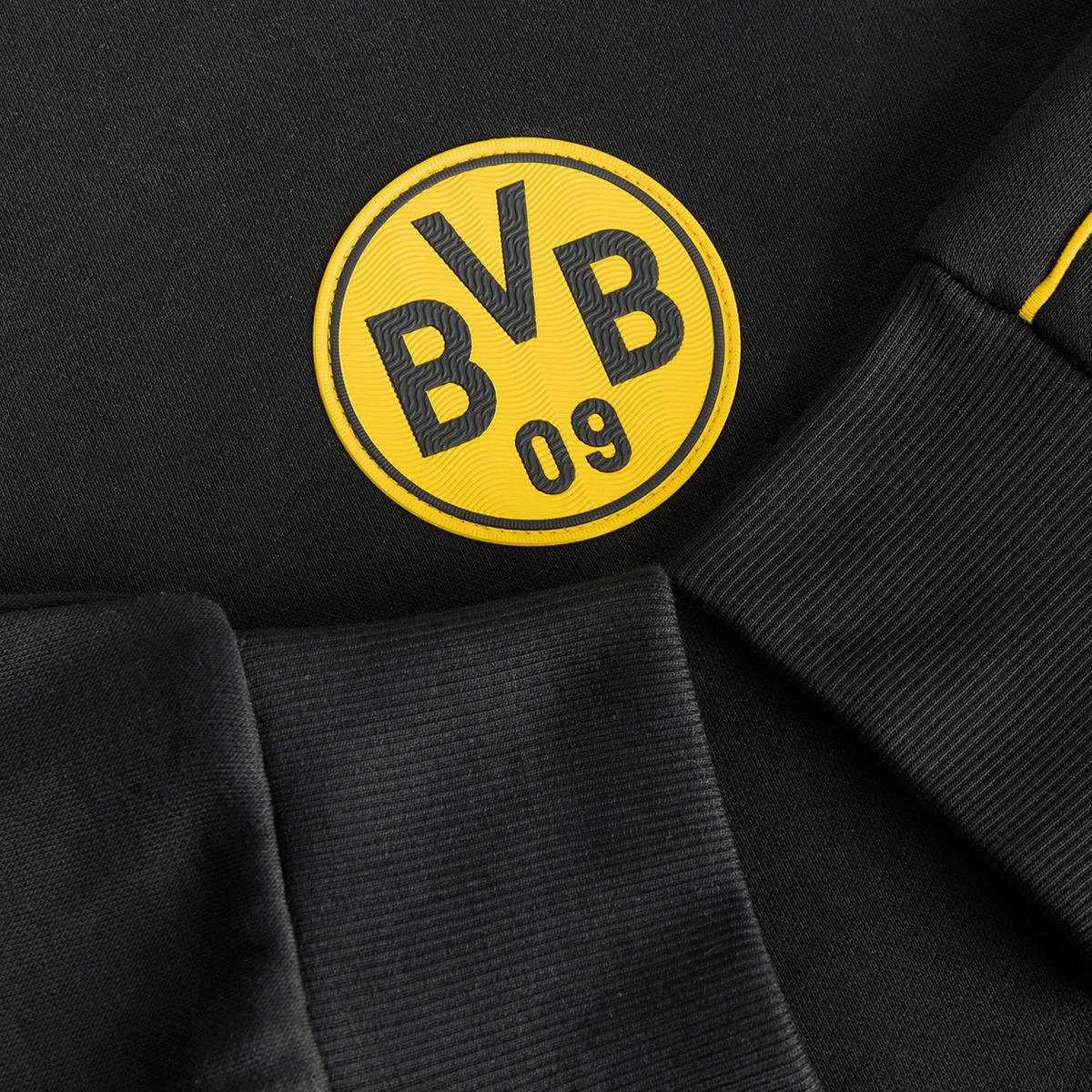 Detailaufnahme eines schwarzen BVB-Hoodies mit auffälligem gelben BVB-Logo und bequemen Stoffdetails.