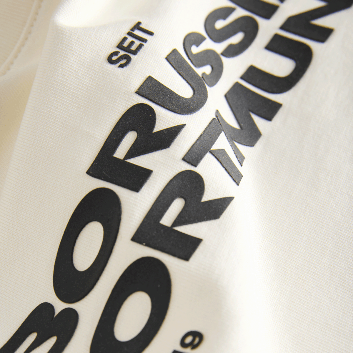 Camiseta Essentials II del BVB en color beige para niños, con el nombre «Borussia Dortmund» en negro y el año 1909; artículo para aficionados al fútbol.
