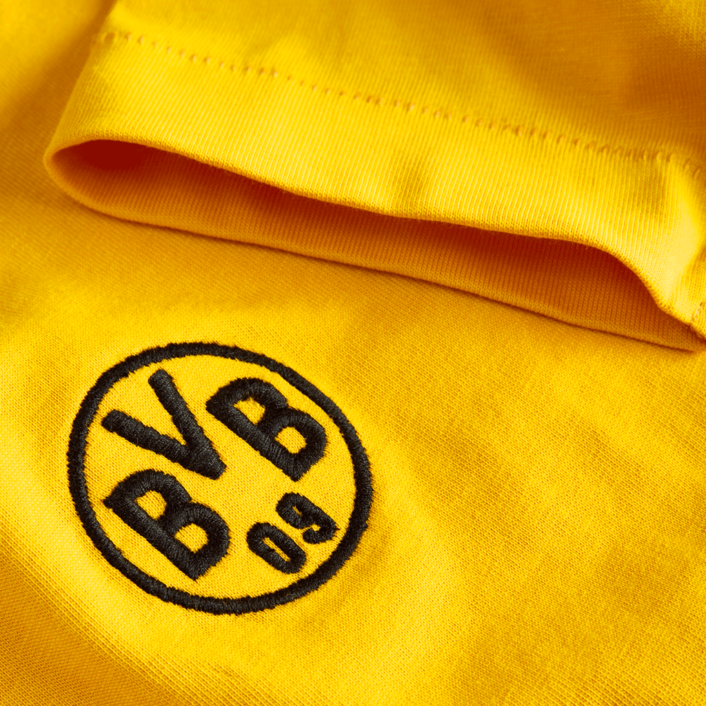 Primer plano de una camiseta amarilla del BVB de la colección Essentials II para niños, con el logotipo del BVB 09 bordado en negro.