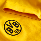 Primo piano di una maglietta gialla BVB Essentials II per bambini con il logo BVB 09 ricamato in nero.
