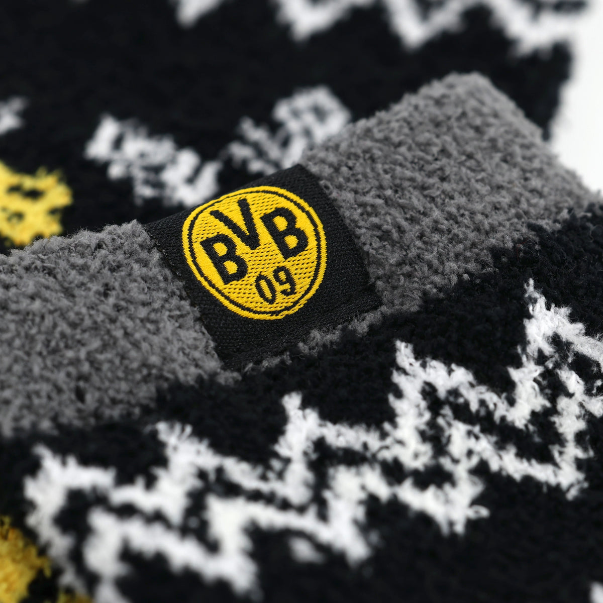 配饰：黑色和黄色相间的多特蒙德（BVB）围巾，采用锯齿形图案，灰色毛绒边，特写镜头中可见缝制的BVB 09标志。