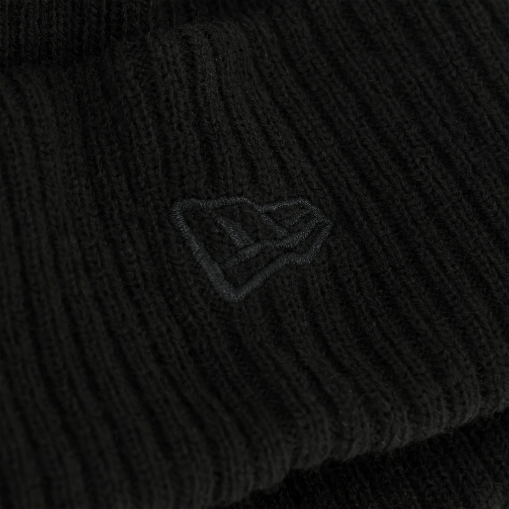 Gros plan sur un tissu noir orné d'un logo brodé, sur fond sombre