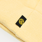 Die BVB-Beanie-Mütze in Pastellgelb zeigt das ikonische schwarzgelbe BVB 09-Logo auf einem schwarzen Etikett. Perfekt als Accessoire für Borussia Dortmund Fans.