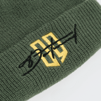 Grüne Beanie mit gesticktem gelbem 09-Logo und schwarzer Schrift, Detailaufnahme.