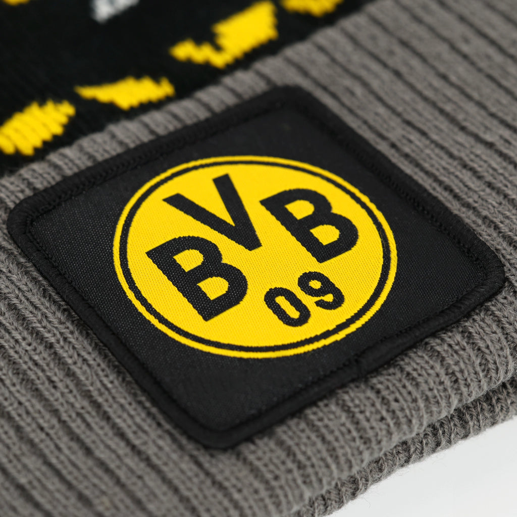 一款灰色多特蒙德（BVB）冬季帽的特写照片，帽上缝有黑黄相间的俱乐部徽标，并配有黑色设计元素。