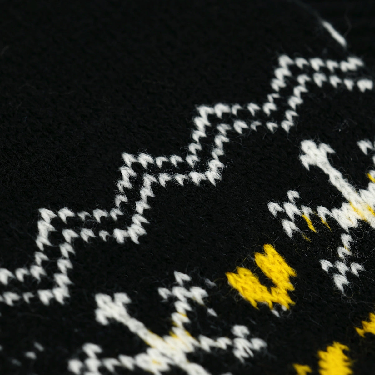 Close-up der BVB-Winterhandschuhe zeigt ein schwarzgelbes Strickmuster mit Schneeflockenmotiven. Perfekt für Fans in der kalten Jahreszeit.